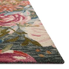 a multicolored rug with flowers and leaves on the bottom, in front of a white background