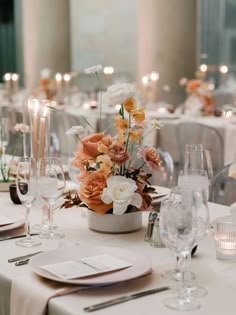 the table is set with white and orange flowers