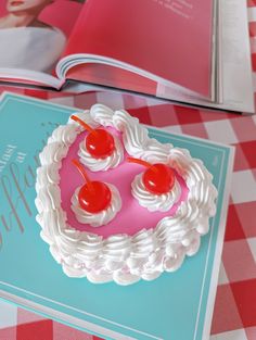 the cake is decorated with cherries and white icing on top of a book