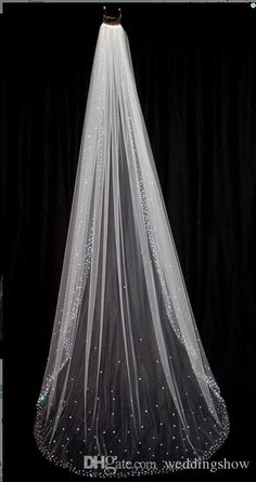 a white wedding veil with sequins on the bottom and long train is hanging in front of a black background