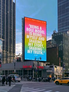 a large billboard on the side of a city street with people walking around and cars parked in front of it