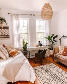 a bed room with a neatly made bed next to a chair and a desk in front of two windows