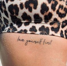 a woman's lower back tattoo with the words love yourself first written on it