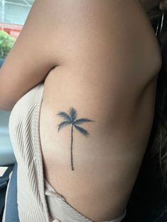 a woman with a small palm tree tattoo on her left side ribcage,