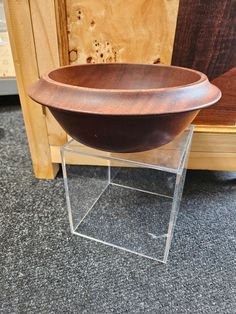 a wooden bowl sitting on top of a glass stand