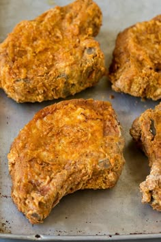 four cooked meat patties sitting on top of a baking pan with one cut in half