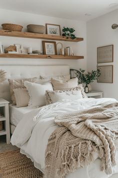 a bed with white linens and blankets in a small room next to wooden shelves