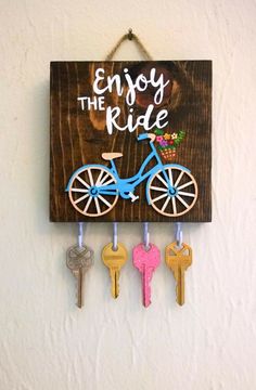 a wooden sign that says enjoy the ride with three keys hanging from it