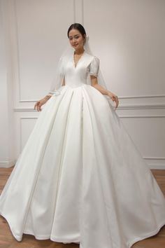 a woman in a white wedding dress posing for the camera with her hands on her hips