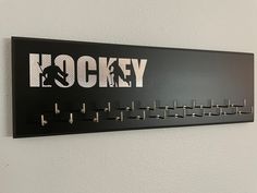 there is a hockey coat rack on the wall with hooks in front of it that says hockey