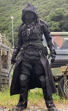 a man dressed in black standing next to a truck