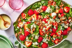 a salad with spinach, strawberries and feta cheese on it next to two glasses of water