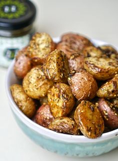 a bowl filled with potatoes sitting on top of a table next to a jar of seasoning