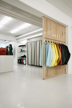 an open room with clothes hanging on the wall and several different colored shirts in it