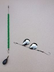 two mirrors sitting on top of a table next to a fishing hook and green bead necklace