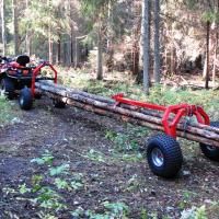 an atv pulling a log in the woods on it's back wheels with another vehicle behind it