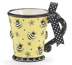 a yellow and black coffee mug with polka dots on the rim, decorated with bees