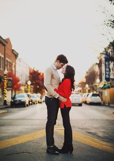 a couple kissing on the street in front of some buildings and pumpkins as well as an instagram