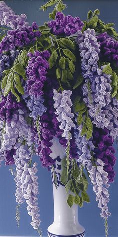 a white vase filled with purple flowers on top of a table