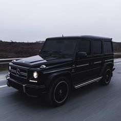 a black mercedes g class driving down the road