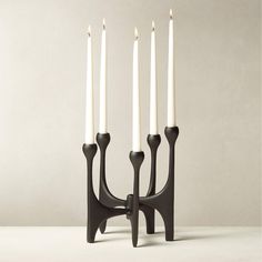 three white candles are in a black candle holder