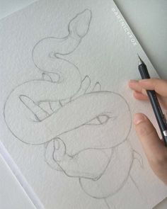 someone is drawing a snake on paper with a marker