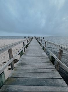 a wooden pier extending into the ocean on a cloudy day