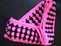 a pink and black crocheted blanket sitting on top of a table