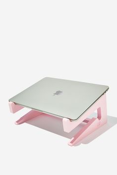 an apple laptop sitting on top of a pink stand