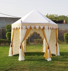 a white and yellow tent sitting on top of a lush green field