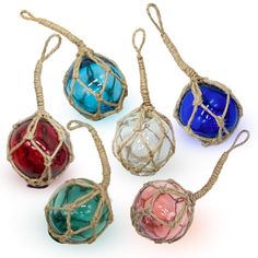 four colorful glass balls tied together with twine and rope on a white background, all in different colors