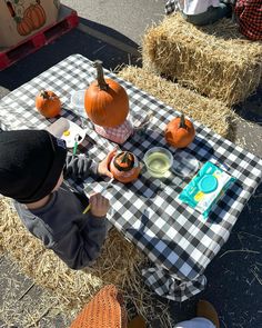 a little boy sitting at a picnic table with pumpkins on it and other decorations