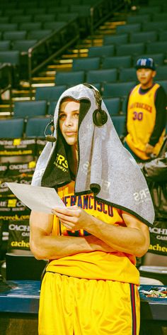 a man in a yellow uniform holding a piece of paper with his face covered by a towel