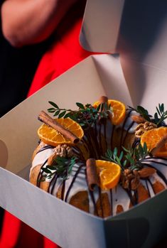 a cake with orange slices and cinnamons in a box