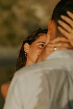 a man and woman standing next to each other with their hands covering their faces in front of them