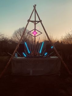 an outdoor stage set up in the middle of a field with lights and sticks on it