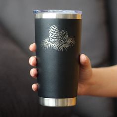 a person holding a black cup with pine cones on it