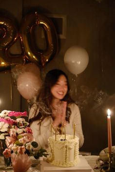 a woman sitting at a table in front of a cake with candles and flowers on it