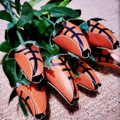 four orange flowers with black lines on them sitting on the ground next to some green leaves