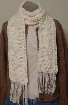 a knitted scarf with fringes on it and a white sweater over the shoulders