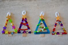 three small christmas trees made out of plastic beads and wooden pegs on a white surface