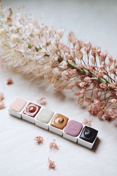 four different types of macaroni and cheese on a white surface next to flowers