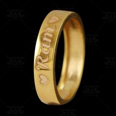 a gold wedding ring with the word love written on it and two hearts carved into it