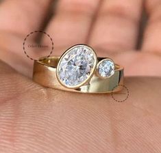 a close up of a person's hand holding a ring with two diamonds on it