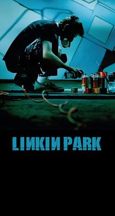 a man in black shirt working on a piece of art with blue background and words linkin park