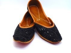 Durable, hand-stitched shoes in the ethnic Indian/Pakistani design, with a leather-padded cushion inside and a genuine leather sole. These stunning shoes have a distinctive and stunning appearance thanks to their black raw silk fabric embroidery with black beads and black sequence on real leather. These shoes are perfect for special occasions as well as everyday usage. Among our most beloved shoe selections for formal events like weddings. These shoes can look great on you with any type of attire. These will make you fall in love, whether you buy them for yourself or as a gift for a friend. To view more of our selection, visit our page! We ship out in a timely matter, wrapped in care for a safe secure trip to your location. Thank you for supporting our small business! Shipped from USA. Siz Embroidered Leather Flats With Flat Heel, Leather Embroidered Flats, Embroidered Leather Slip-on Flats, Festive Leather Flats With Handwork, Festive Handwork Leather Flats, Festive Embroidered Leather Flats, Traditional Sandals With Rubber Sole And Flat Heel, Traditional Sandals With Flat Rubber Sole, Traditional Flat-heel Sandals With Rubber Sole