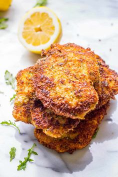 three crab cakes stacked on top of each other next to lemon wedges and parsley