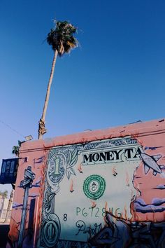 a palm tree is standing next to a money bill mural on the side of a building