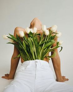 a person laying on the ground with flowers in front of their back and legs behind them