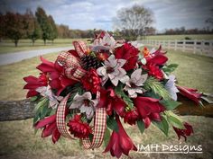 a bouquet of red flowers and greenery on a fence in front of a field